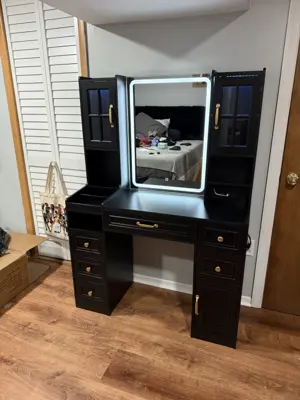 Fully assembled black vanity desk with lighted mirror and gold hardware in a NYC bedroom