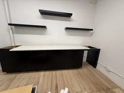 Assembled black media console with marble top and floating wall shelves installed in NYC office or living room