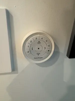 Hunter Douglas motorized blind remote control mounted on white wall in NYC home