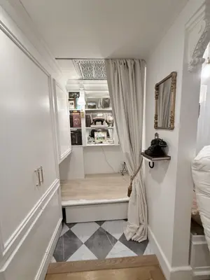 renovated nyc apartment hallway with curtain rod, shelving, and checkered tile flooring after handyman work