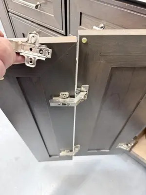 close-up of cabinet door soft-close hinges being adjusted on dark wood cabinetry in nyc