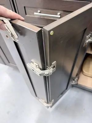 close-up of cabinet door hinges adjusted and aligned on dark wood kitchen cabinetry