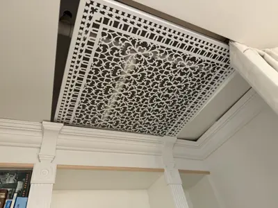 Decorative ventilation screen cover installed on elegant ceiling with crown molding
