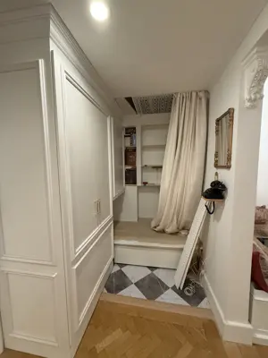 Elegant hallway with custom white panel doors, herringbone hardwood floors, and built-in shelving after renovation