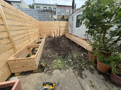 outdoor backyard renovation in progress with new cedar wood raised garden beds and bench seating in nyc