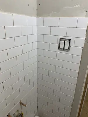 white subway tile bathroom wall installation nearing completion in nyc home renovation