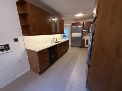 Renovated NYC kitchen with dark wood cabinets, white countertops, and stainless steel appliances