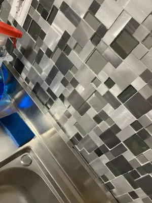 metallic mosaic backsplash tile installation completed above stainless steel kitchen sink in nyc