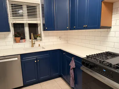 completed nyc kitchen renovation with navy blue painted cabinets, white subway tile backsplash, and gold hardware