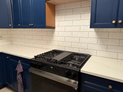 newly installed stainless steel gas range stove in a renovated nyc kitchen with blue cabinets and white subway tile backsplash