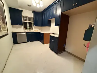 freshly painted navy blue kitchen cabinets with white marble-look flooring in nyc home