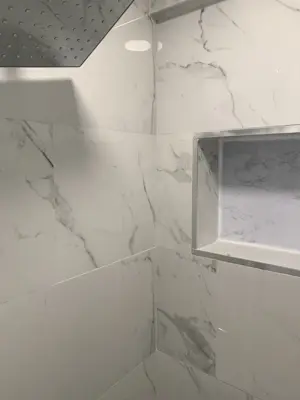 completed marble-look shower tile installation with built-in niche and rain showerhead in nyc