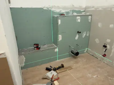 bathroom drywall installation in progress with green moisture-resistant board and laser level in nyc