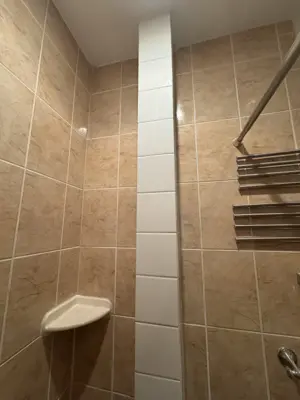 completed bathroom tile installation with white accent column and corner shelf in nyc