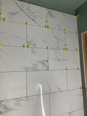 large-format marble-look wall tiles being set with leveling spacer clips during nyc bathroom renovation