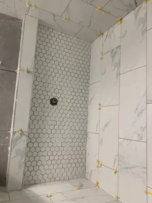 shower floor hexagon mosaic tile and marble-look wall tile installation in nyc bathroom