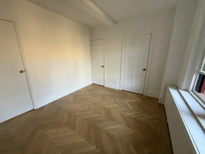 Completed herringbone hardwood floor installation in a bright NYC apartment room