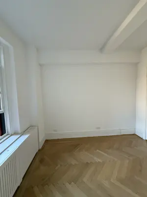 Freshly painted bright white room with herringbone hardwood floors in NYC apartment