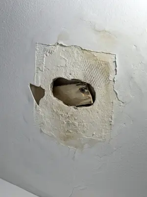 Damaged ceiling with large hole and water stains before drywall repair in NYC home
