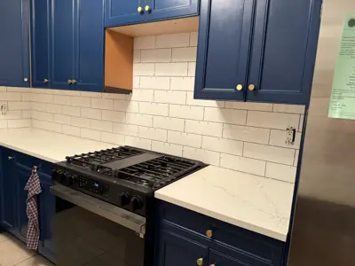 freshly painted navy blue kitchen cabinets with white subway tile backsplash and quartz countertops in nyc