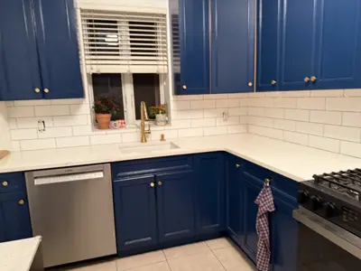 freshly painted navy blue kitchen cabinets with gold hardware and white subway tile backsplash in nyc home