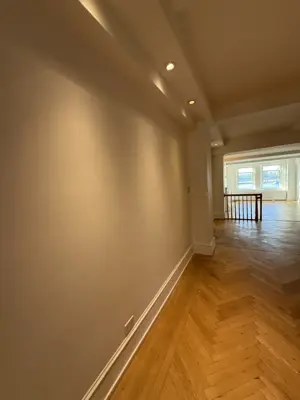 Freshly painted hallway walls with smooth white finish and herringbone hardwood floors in NYC home