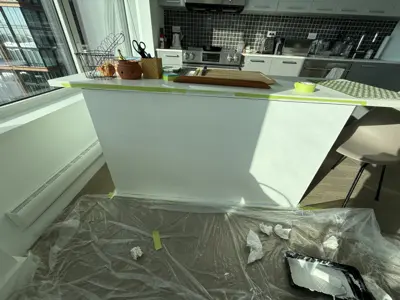 kitchen island being painted white with painter's tape and drop cloth protection during nyc painting job