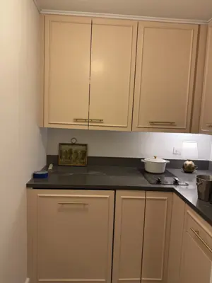 close-up of installed beige kitchen cabinets with gold hardware and dark stone countertop in nyc
