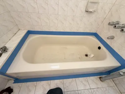 Bathtub taped with blue painter's tape for bathroom painting preparation