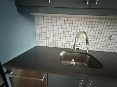 newly installed stainless steel kitchen sink and chrome faucet with mosaic tile backsplash in nyc home