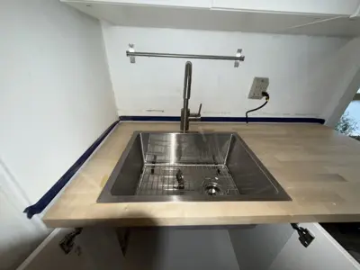 Stainless steel kitchen sink and pull-down faucet installation on butcher block countertop