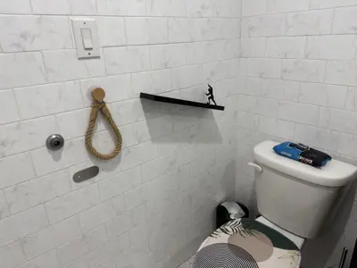 floating black shelf mounted on marble-tile bathroom wall above toilet in nyc apartment