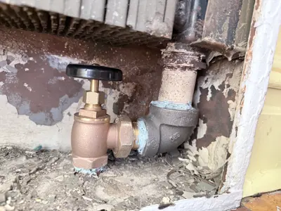 Brass shut-off valve installation under radiator with pipe fittings