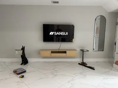 sansui tv professionally wall mounted above floating media console in modern living room