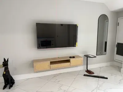 large flat screen tv being leveled with laser level during wall mounting installation in modern nyc living room