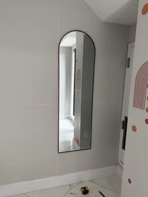 full-length arch mirror professionally wall-mounted in nyc apartment entryway using laser level