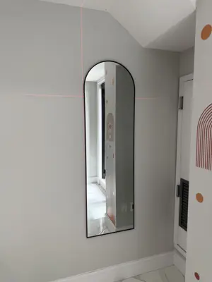 arched full-length mirror professionally wall-mounted in a nyc apartment hallway with laser level