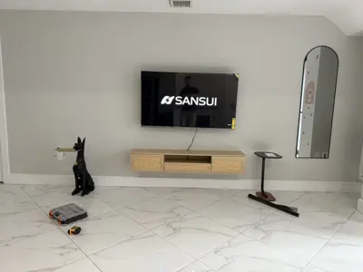 large sansui tv professionally wall-mounted above floating media console in modern living room