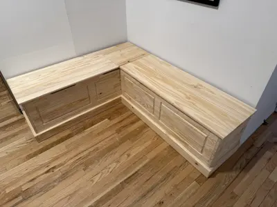 Custom-built L-shaped wooden storage bench with panel detailing installed in NYC home corner
