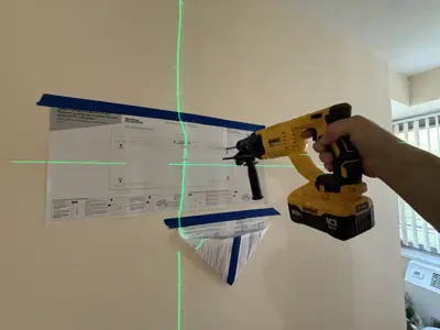 Handyman using laser level and drill to mark wall mount installation points in NYC apartment