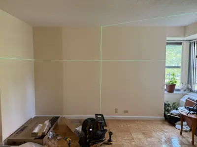 laser level setup on living room wall for precise tv or shelf mounting in nyc apartment
