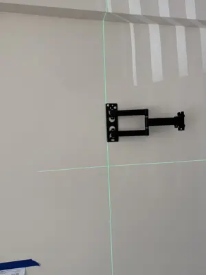 TV wall mount bracket being leveled with green laser level on white wall in NYC