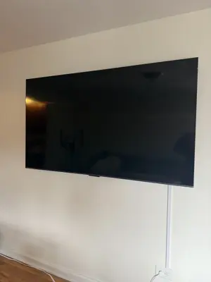 Large flat-screen TV professionally wall-mounted in a clean NYC living room with cord management