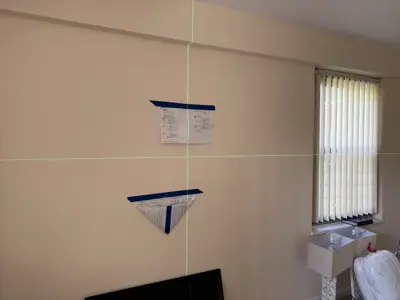 laser level and mounting template taped to wall during tv or shelf installation in nyc home