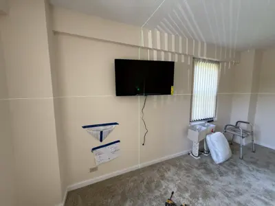Flat screen TV mounted on living room wall with laser level guide lines visible during installation process