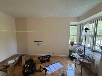 laser level setup on living room wall for precise tv or shelf mounting in nyc apartment