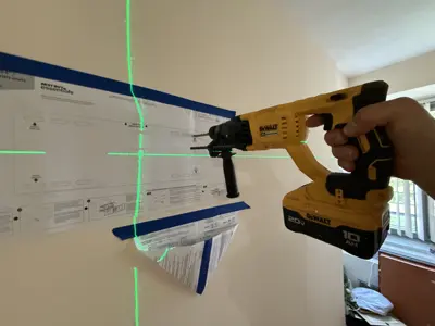 Handyman using DeWalt drill with laser level guide to mount TV bracket on NYC apartment wall