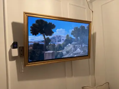 Samsung Frame TV mounted on white paneled wall displaying landscape artwork in NYC home