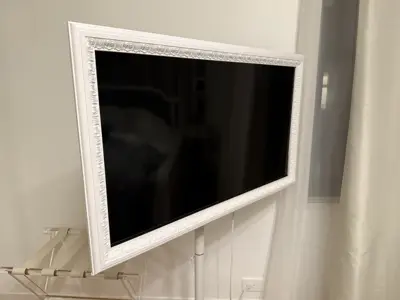 Decorative framed Samsung Frame TV mounted on white wall in NYC apartment