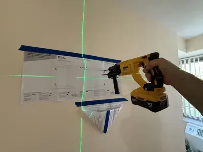 Handyman using DeWalt drill with laser level guide to mount bracket on wall in NYC